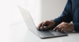 Ordenador portátil sobre cuyo teclado aparecen unas manos escribiendo